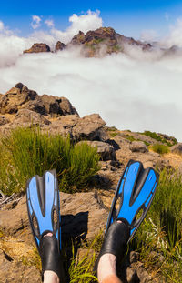 Low section of man with diving flippers sitting on mountain