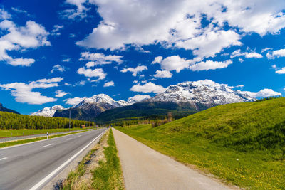 Road leading towards mountains against sky