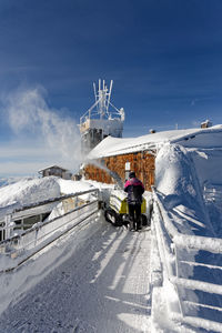 People on snowcapped mountain against sky during winter