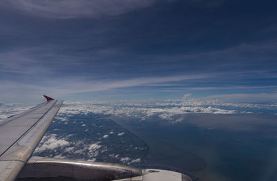 Aerial view of aircraft wing over mountains against sky