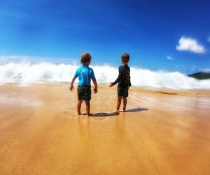 Rear view of boys standing at beach