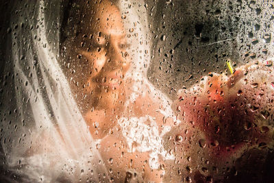 Portrait of woman seen through wet glass