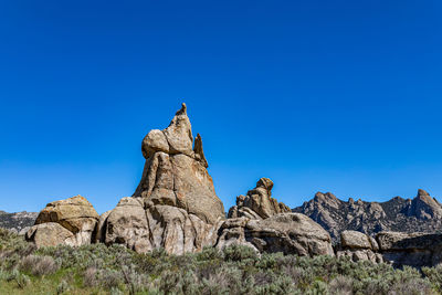 Low angle view of rock formation against clear blue sky