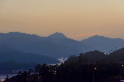 Scenic view of silhouette mountains against clear sky at sunset