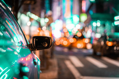 Close-up of car moving on road against illuminated lights at night