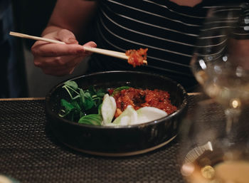 Midsection of person holding ice cream in bowl on table