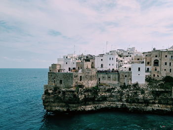 Scenic view of sea by buildings against sky