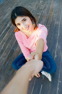 High angle portrait of smiling young woman sitting outdoors