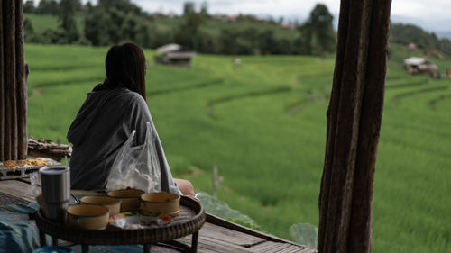 Rear view of woman sitting on wooden table