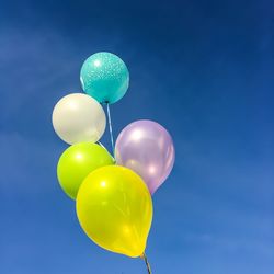 Low angle view of balloons against blue sky