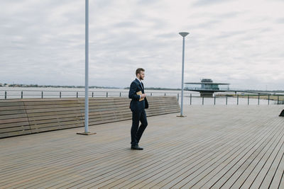 Full length of man standing on pier over sea against sky