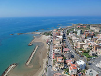 High angle view of buildings by sea against blue sky