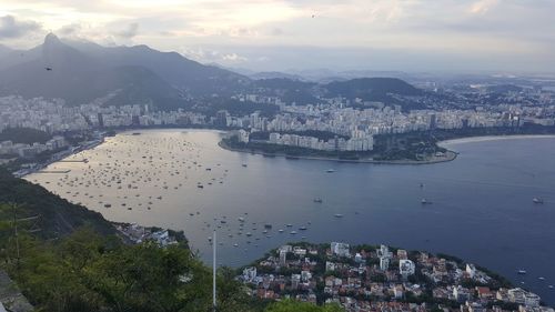 High angle view of city by river and buildings against sky