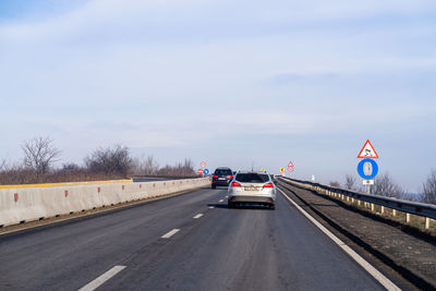 Road sign on highway against sky