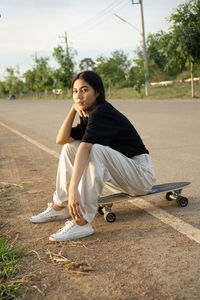 Portrait of young woman sitting on road