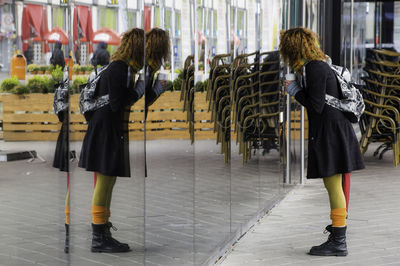 Side view of woman with backpack reflecting on glass window