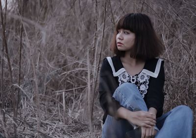 Portrait of young woman sitting on dry field