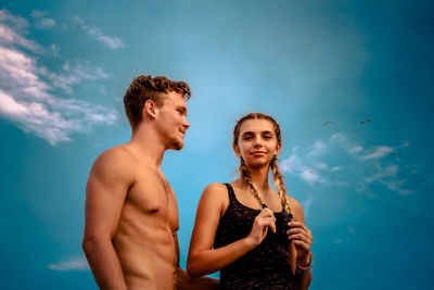 Young couple kissing against blue sky