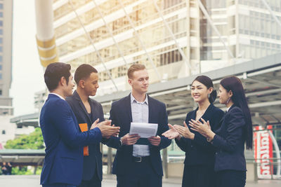 Business colleagues discussing while standing on footpath in city