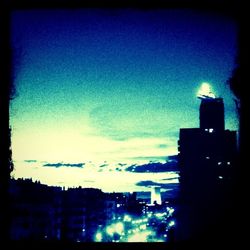 Illuminated cityscape against blue sky at dusk