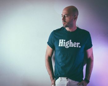 Man wearing t-shirt with text while standing against wall