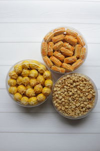 Three jars of nastar, kaasstengels, and fried peanuts on a table.