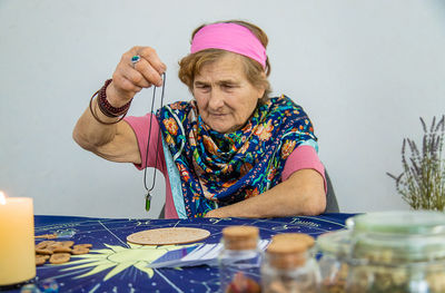 Portrait of smiling young woman making heart shape on table