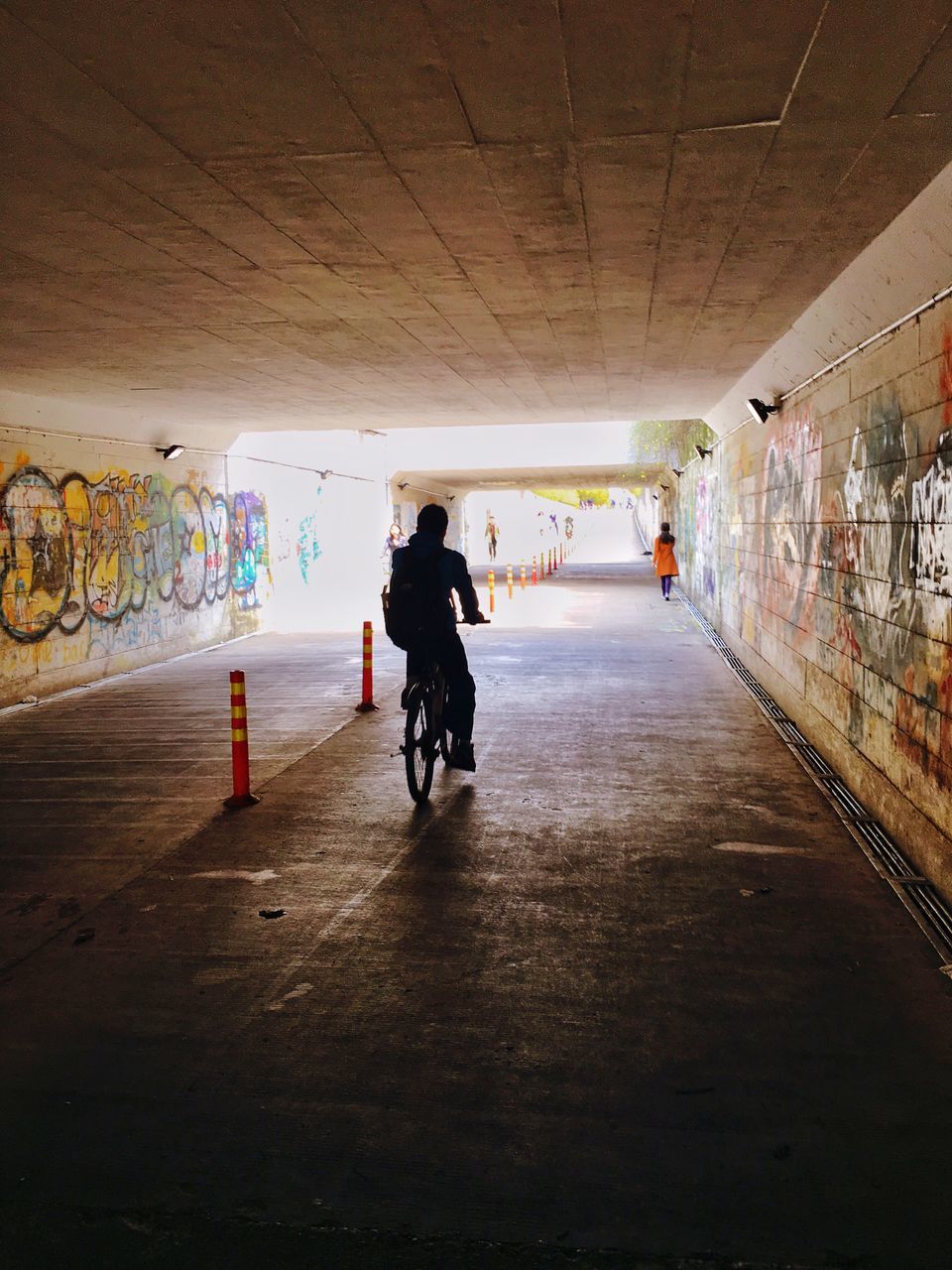 full length, walking, the way forward, indoors, lifestyles, men, architecture, built structure, tunnel, rear view, leisure activity, person, wall - building feature, diminishing perspective, illuminated, ceiling, vanishing point, transportation