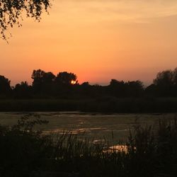 Scenic view of lake against orange sky