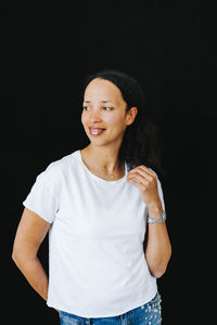 Portrait of a smiling young woman against black background