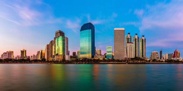 Sea by modern buildings against sky in city