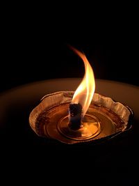 Close-up of lit candle in darkroom