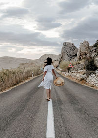Rear view of man standing on road against sky