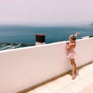 Rear view of woman standing by sea against sky