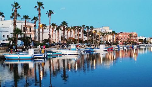 Boats in marina by buildings against clear sky