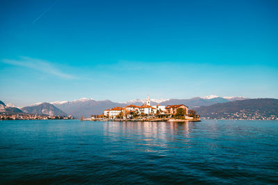 Scenic view of sea by buildings against blue sky