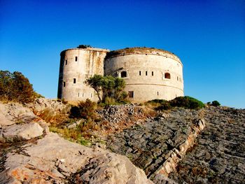 Low angle view of old ruins against clear blue sky