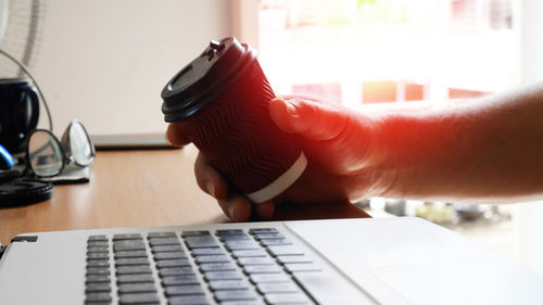 Close-up of man using laptop on table