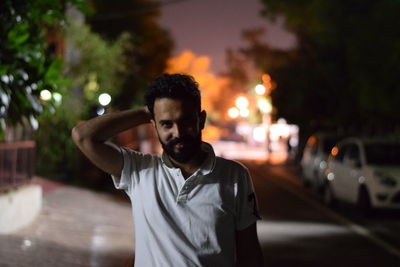 Portrait of young man standing on street at night