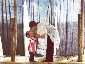 Side view of mother kissing son