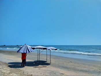 Lifeguard hut on beach against blue sky