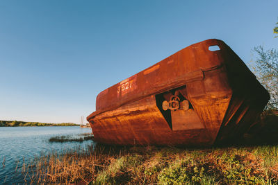 Abandoned boat in lake against clear sky