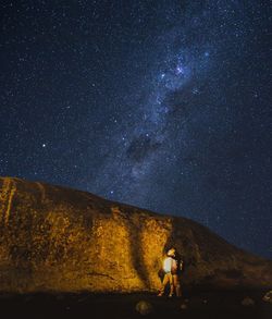 Men standing on mountain against star field