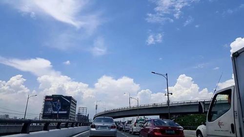 Cars on road against cloudy sky