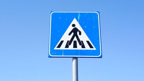 Low angle view of road sign against blue sky