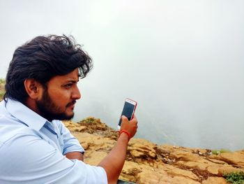 Young man taking selfie from mobile phone at mountain peak