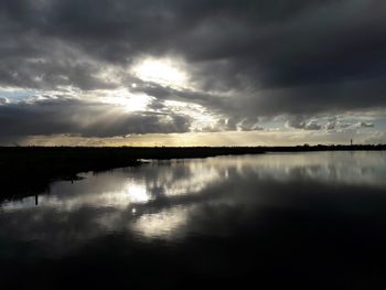 Scenic view of lake against dramatic sky during sunset