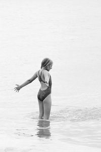 Girl with arms outstretched standing in sea 