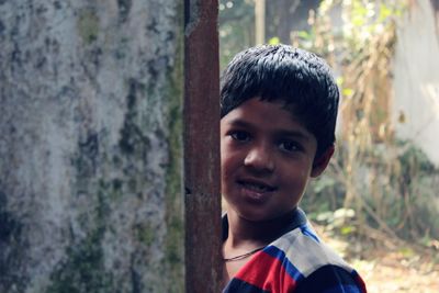 Portrait of boy smiling standing by wall