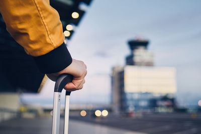 Cropped hand holding luggage handle in city